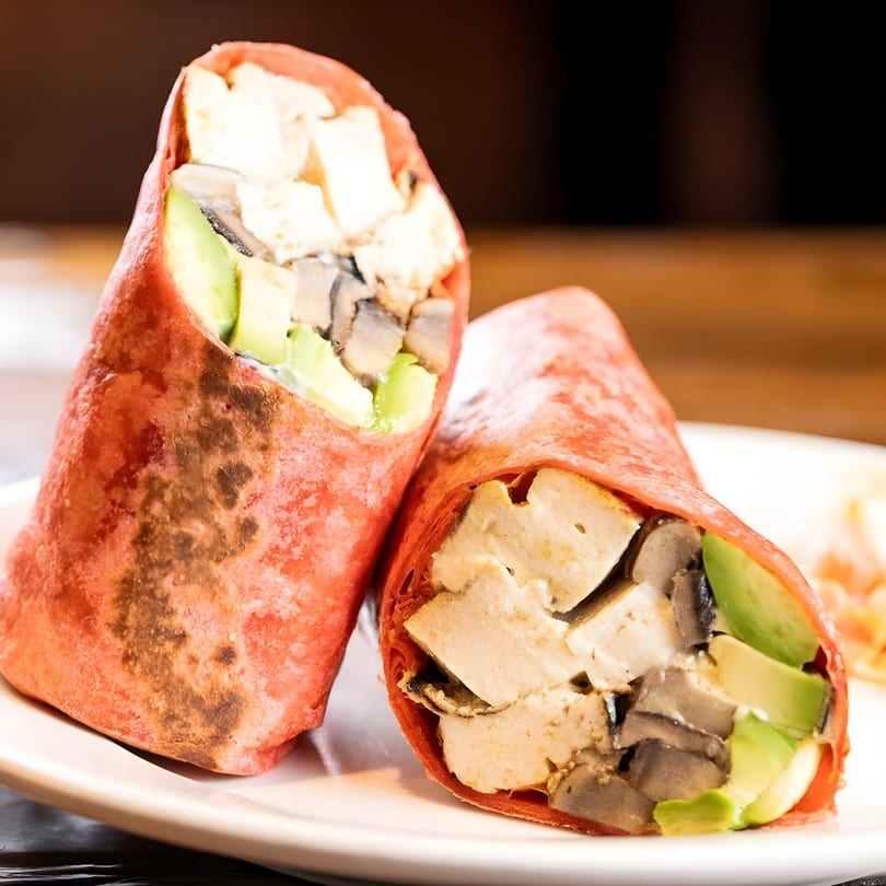 Two Tinga Fresh Mexican wraps with chicken, mushrooms, and avocado on a white plate.