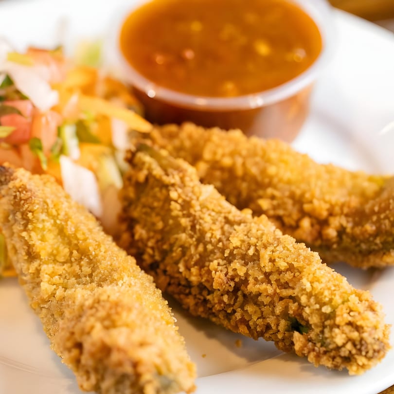 Three crispy, breaded Mexican chili peppers with a side of salsa and fresh pico de gallo.